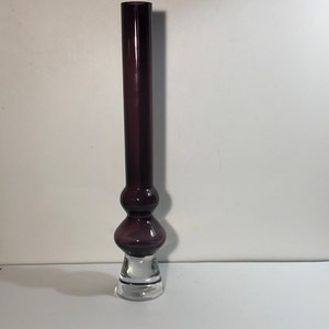 May include: A tall, purple glass vase with a clear glass base. The vase has a bulbous middle section.