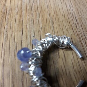 May include: A silver wire wrapped ring with multiple light blue and purple gemstones.