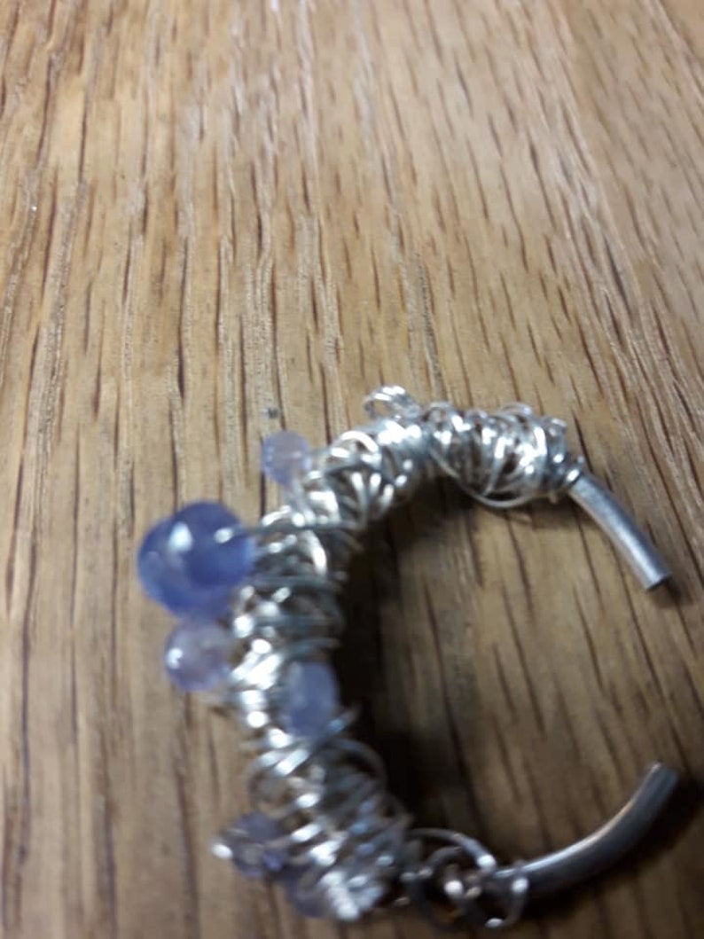 May include: A silver wire wrapped ring with multiple light blue and purple gemstones.