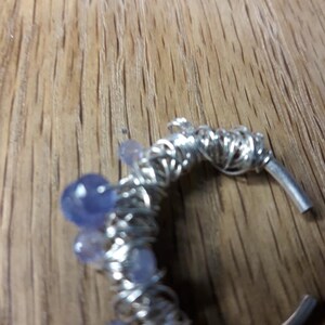 May include: A silver wire wrapped ring with purple and blue stones.
