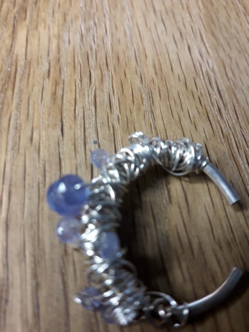 May include: A silver wire wrapped ring with purple and blue stones.
