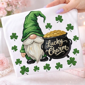 May include: White fabric with a St. Patrick's Day gnome design. The gnome wears a green hat and has a long white beard. A black pot of gold with the words "Lucky Charm" is next to the gnome. Green shamrocks are scattered around the design.
