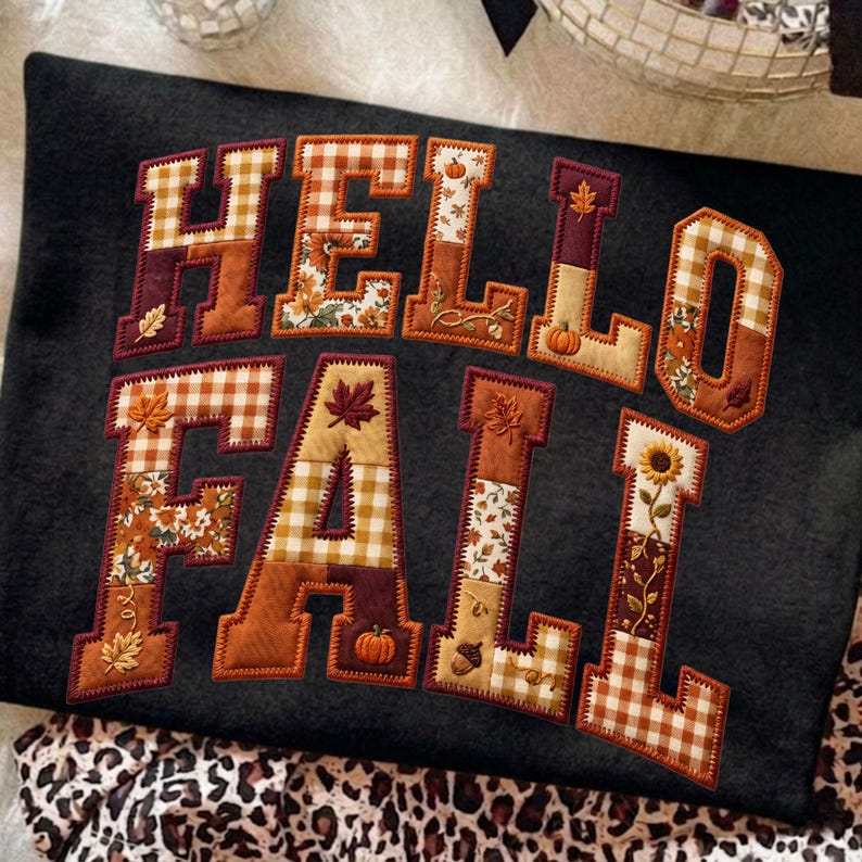 Peut inclure: Un sweat-shirt noir avec le texte HELLO FALL en grandes lettres majuscules. Chaque lettre est remplie d'un patchwork de tissus aux motifs automnaux, incluant du vichy orange et blanc, des fleurs, des citrouilles, des feuilles et des tournesols.