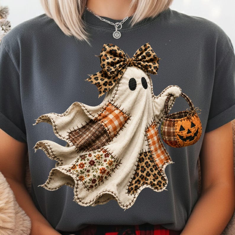 Pu&ograve; includere: Una t-shirt grigio scuro con la grafica di un fantasma composto da vari tessuti a motivi, tra cui quadri, fiori e stampa leopardata. Il fantasma indossa un fiocco leopardato sulla testa e tiene in mano un piccolo secchiello arancione a zucca.