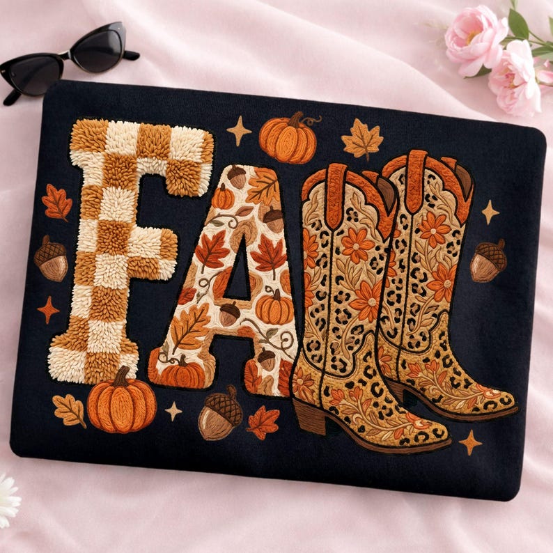 K&ouml;nnte beinhalten: Schwarzes Kissen mit dem Wort "FALL" in einem Herbstthema. Der Buchstabe "F" hat ein braun-beiges Karomuster. Der Buchstabe "A" ist mit Herbstbl&auml;ttern und K&uuml;rbissen verziert. Das "LL" ist ein Paar Cowboy-Stiefel.