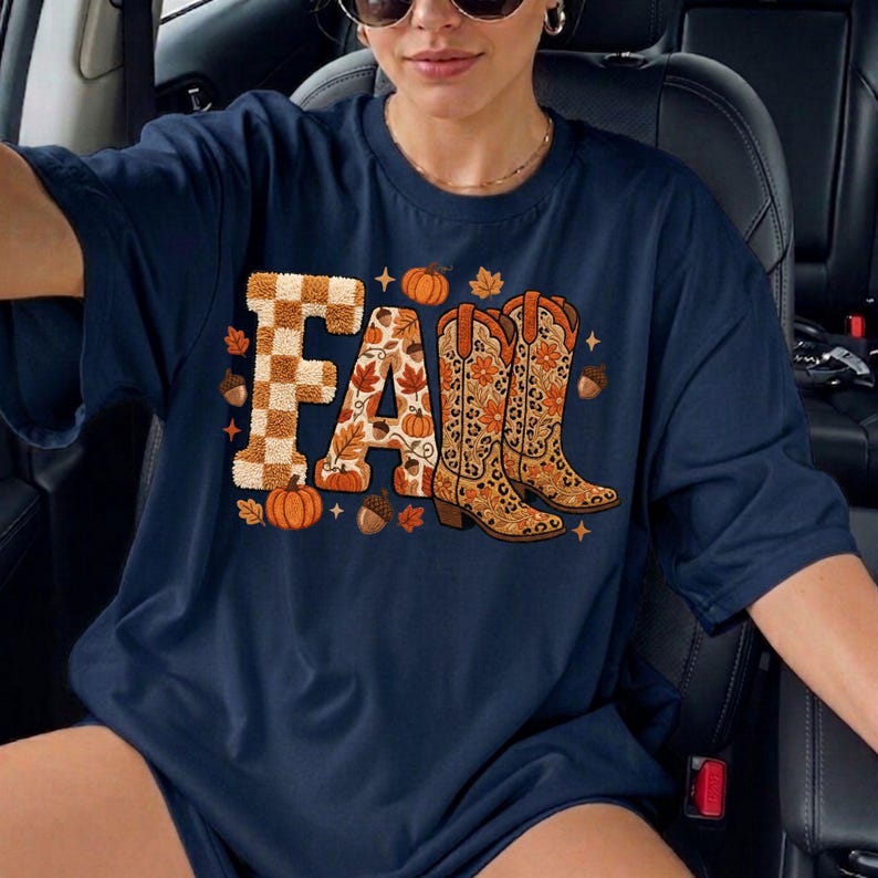 K&ouml;nnte beinhalten: Marineblaues T-Shirt mit dem Wort "FALL" in einem herbstlichen Design. Der Buchstabe "F" ist kariert, das "A" hat ein Blumenmuster und die "L"s sind mit Cowboy-Stiefeln, K&uuml;rbissen und Bl&auml;ttern verziert.