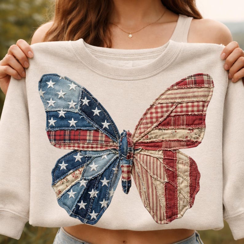 May include: A cream-coloured sweatshirt with a large butterfly design. The butterfly wings are made from patchwork denim and red plaid fabric, with white star accents. The design has a patriotic theme.