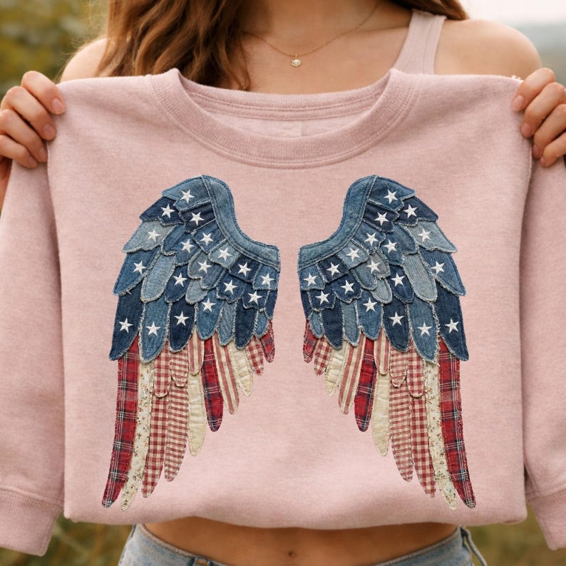 May include: A pale pink sweatshirt with a pair of angel wings appliqu&eacute;d on the front. The wings are made from blue denim, white stars, and red and white striped and checked fabric, creating a patriotic design.