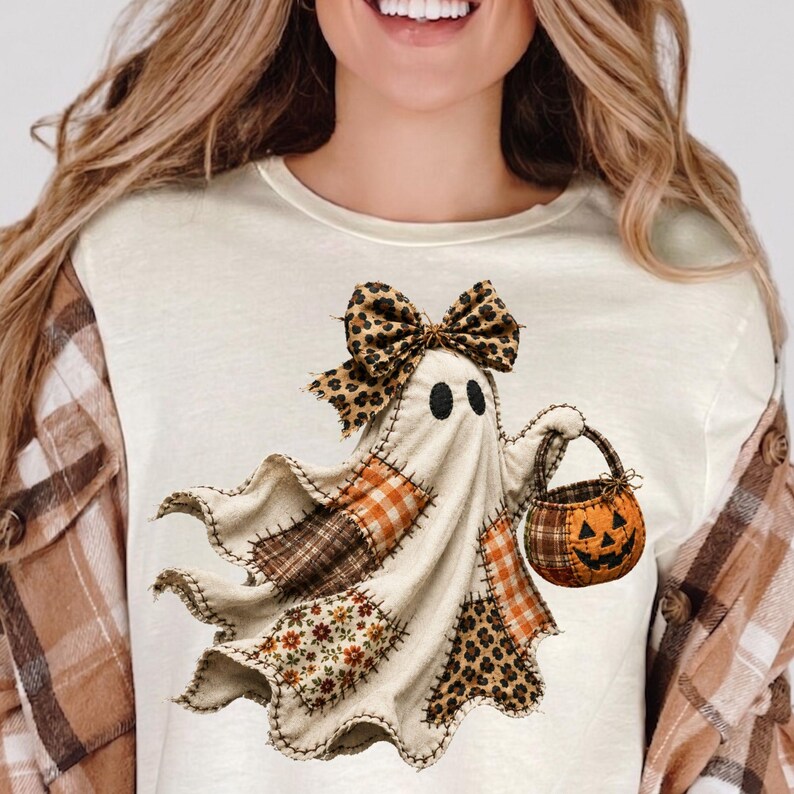 Pu&ograve; includere: Una t-shirt color crema con la grafica di un fantasma composto da vari ritagli di tessuto, tra cui quadri arancioni, fiori marroni e stampa leopardata. Il fantasma indossa un fiocco leopardato e tiene in mano un secchiello a zucca.