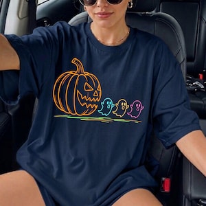 Op de afbeelding: Marineblauwe t-shirt met een Halloween-ontwerp. De afbeelding toont een oranje pompoen en drie kleurrijke geesten. De neon contouren cre&euml;ren een feestelijke en opvallende uitstraling.