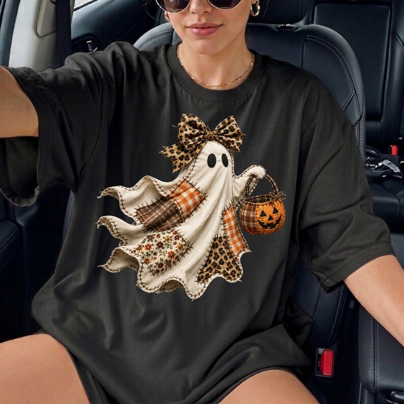 Pu&ograve; includere: Una t-shirt nera a maniche corte con la grafica di un fantasma che indossa un fiocco leopardato. Il fantasma &egrave; decorato con vari inserti a quadri e floreali nei toni del marrone, arancione e crema e tiene in mano un secchiello a zucca.