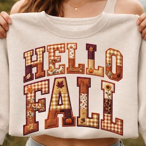 Peut inclure: Un sweat-shirt &agrave; col rond couleur cr&egrave;me avec le texte HELLO FALL en grandes lettres majuscules. Chaque lettre est remplie d'un motif patchwork aux th&egrave;mes automnaux, incluant du vichy orange, des imprim&eacute;s floraux marron, des citrouilles et des feuilles.