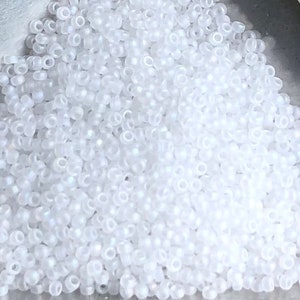 May include: A large quantity of small, white, opaque seed beads. The beads are round and have a smooth, slightly iridescent finish.