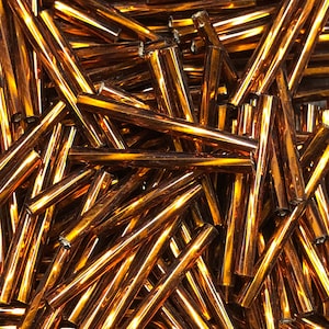 May include: A pile of amber glass rods, perfect for crafting and jewelry making. The rods are smooth and shiny, with a warm, golden hue.