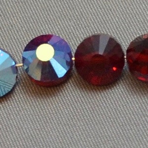 May include: Four round glass beads strung on a wire. The beads are iridescent blue, iridescent blue, red, and red.