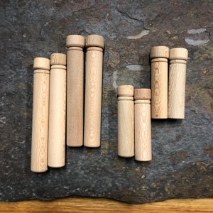 May include: A set of eight wooden spools in various sizes. The spools are made of light brown wood and have a smooth, polished finish.