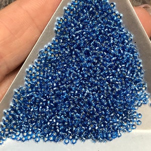 May include: A large pile of small, round, blue glass beads with a silver metallic finish.