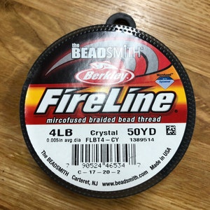 May include: A spool of black FireLine microfused braided bead thread by Berkley. The label reads "4LB Crystal 50YD" and "0.005in avg. dia FLBT4-CY 1389514".
