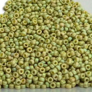 May include: A large pile of small, round, light green glass beads. The beads have a slightly iridescent finish.