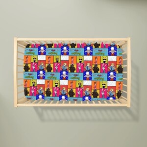 Puede incluir: Una s&aacute;bana de cuna con un patr&oacute;n de cuadr&iacute;cula repetitivo de personajes de dibujos animados de Zootopia, incluidos Judy Hopps y Nick Wilde, intercalados con el texto You can be anything en fuente amarilla sobre fondos rectangulares azules, naranjas y blancos.