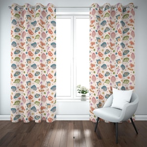 May include: Two beige curtain panels with a repeating pattern of cartoon faces in various colors. The faces are interspersed with colorful dots and diamond shapes. The curtains are hanging in front of a window.
