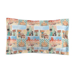 May include: A rectangular pillowcase featuring a repeating pattern of desert landscapes, Route 66 signs, cacti, and cartoon cars. The design includes the text "Float like a Cadillac, sting like a Beamer" and "Cozy Cone Motel" in a soft colour palette.