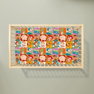 May include: A cot sheet featuring a repeating grid pattern of Toy Story characters including Woody, Buzz Lightyear, Rex, Hamm, Mr. Potato Head, Bo Peep, Slinky Dog, and the green aliens, set against a light-coloured wooden cot frame.