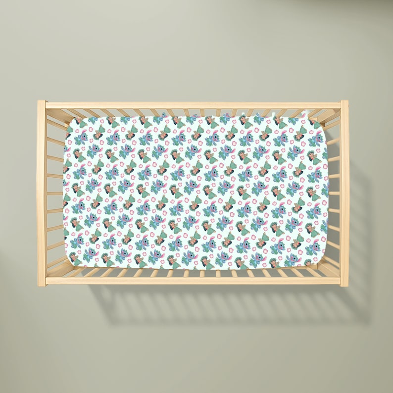 May include: A light blue cot sheet featuring a repeating pattern of a cartoon character in blue, green, and pink. The cot sheet is inside a wooden cot frame.
