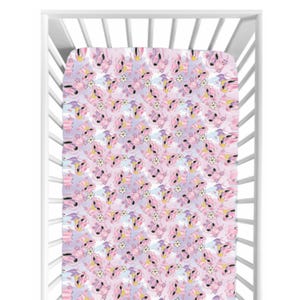 May include: A fitted crib sheet with a repeating pattern of pink unicorns, white flowers, and yellow accents on a lavender background. The sheet is inside a white crib.