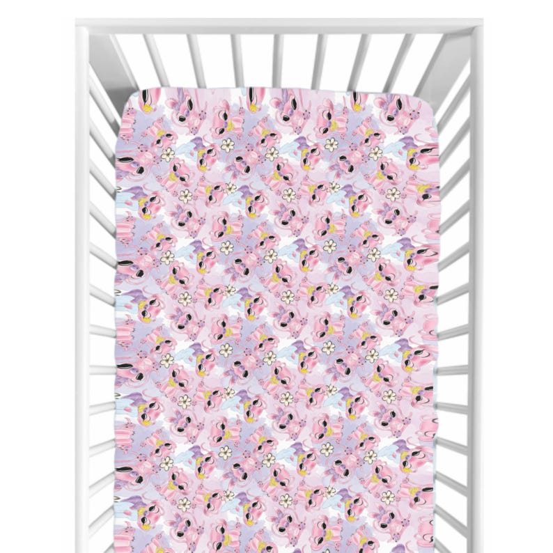 May include: A fitted crib sheet with a repeating pattern of pink unicorns, white flowers, and yellow accents on a lavender background. The sheet is inside a white crib.