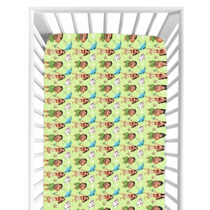 May include: A fitted cot sheet featuring a repeating pattern of a cartoon character, flowers, and umbrellas on a light green background. The sheet is inside a white cot.
