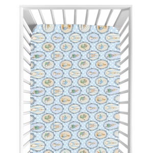May include: A baby crib with a fitted sheet featuring a repeating pattern of oval frames with illustrations of rabbits and other animals. The background is light blue with white polka dots and blue stripes.