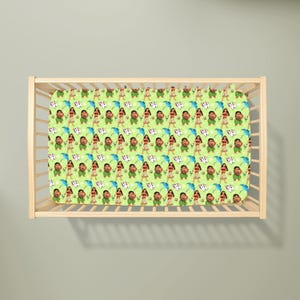 May include: A light green crib sheet featuring a repeating pattern of cartoon characters. The design includes figures of a woman in a red skirt and a man in green, along with blue umbrellas and white flowers.