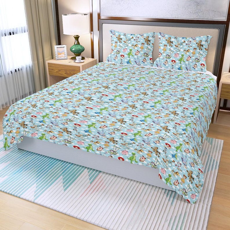 May include: A light blue bedspread and two pillowcases featuring a repeating pattern of cartoon characters. The bedding set has a white polka dot design and is placed on a bed with a white mattress.