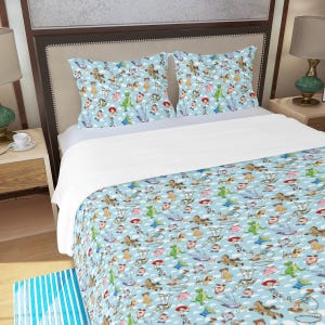 May include: A light blue bedding set featuring a repeating pattern of cartoon characters, clouds, and toys. The set includes a comforter and two pillowcases. The design is a whimsical and colorful illustration.