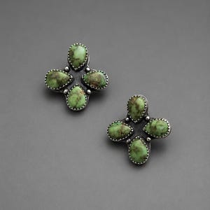 May include: A pair of stud earrings featuring four teardrop-shaped green stones with brown matrix patterns, each bezel-set in scalloped sterling silver. The stones are arranged in a cross-like cluster formation with a small silver bead at the center.