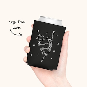 May include: A black can cooler with a white skeleton design holding a martini glass. The text "Dani's Dirty 30" and "Est. 1993" are printed on the cooler. The words "regular can" are written in cursive with an arrow pointing to the can.