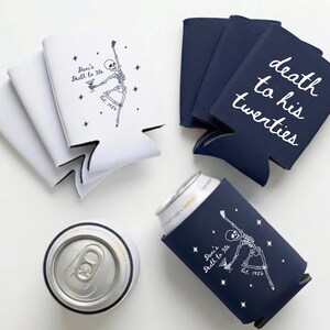 May include: White and navy blue can coolers with text and skeleton graphics. One cooler says "Dani's Death to 30s" and another says "death to his twenties". A silver can is in a navy blue cooler.