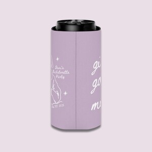 May include: A lavender can cooler with black trim. The cooler has white text that reads "Dani's Bachelorette Party" with a graphic and "Est. 2025". The words "girls go must" are also written on the cooler.