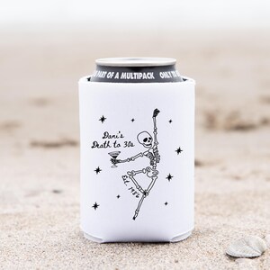 May include: White can cooler with a black skeleton illustration holding a martini. The text "Dani's Death to 30s" and "Est. 1986" are also printed on the cooler. Black star accents surround the skeleton.
