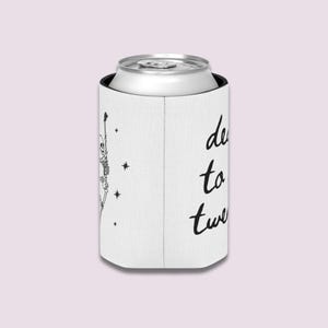 May include: White can cooler with a black skeleton graphic and the words "dead to twenty" in black script. The cooler is holding a silver can.
