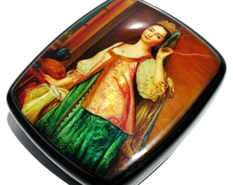 May include: A wooden box with a painted scene of a woman in a traditional Russian dress. The woman is standing in a room with a window and a table. The box is decorated with a black lacquer finish.