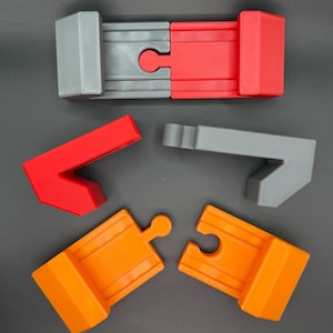 Puede incluir: Cinco piezas de pista para una pista de carreras de coches de juguete. Las piezas de la pista son de plástico y son de color gris, rojo y naranja.