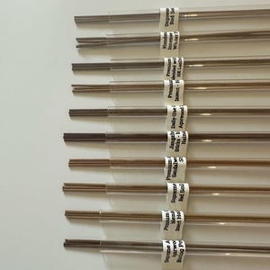 May include: A collection of incense sticks in clear plastic tubes, each labeled with text. The sticks are various shades of brown. The labels include text such as "Supreme Agarwood" and "Premium blend Insect Hol".