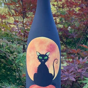 Halloween cat on pumpkin lighted wine bottle