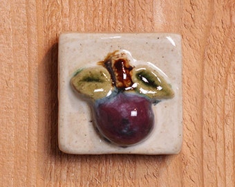 Handmade 2x2 ceramic plum tile comes with a hanger on the back or ready for a tile installation