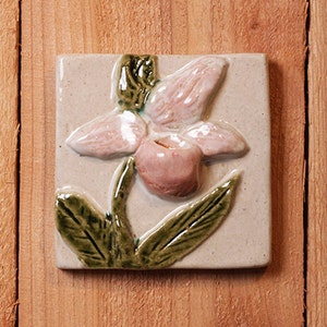 Handmade 4x4 relief ceramic Ladyslipper tile comes with a hanger on the back, suitable for a tile installation