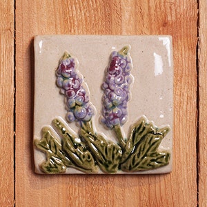 Handmade 4x4 relief ceramic Lupine tile comes with a hanger on the back, suitable for tile installation