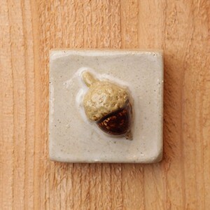 Handmade 2x2 ceramic acorn tile comes with a hanger on the back