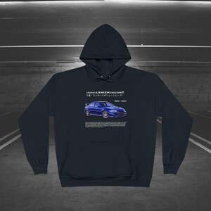 Op de afbeelding: Een marineblauw hoodie met een witte afbeelding van een blauwe Mitsubishi Lancer Evolution VII auto. De tekst "A MITSUBISHI LANCER EVOLUTION VII 三菱 ランサー エボリューション VII  1997 - 2001" is onder de auto afgedrukt.